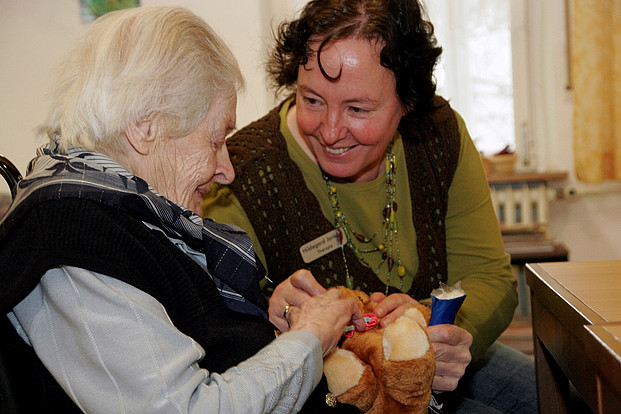 Pflegerin kümmert sich liebevoll um Seniorin